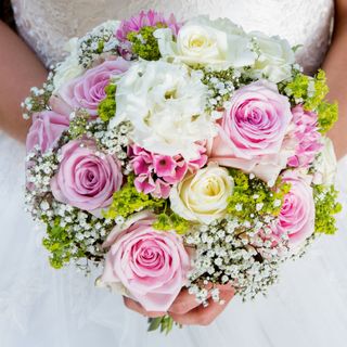 Brautstrauß mit rosa und weißen Rosen, in den Händen der Braut gehalten
